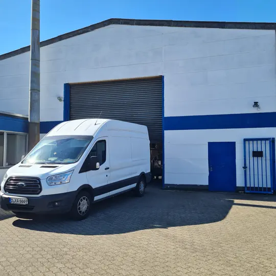 weißer Lieferwagen von Alami Transporte vor einer Lagerhalle